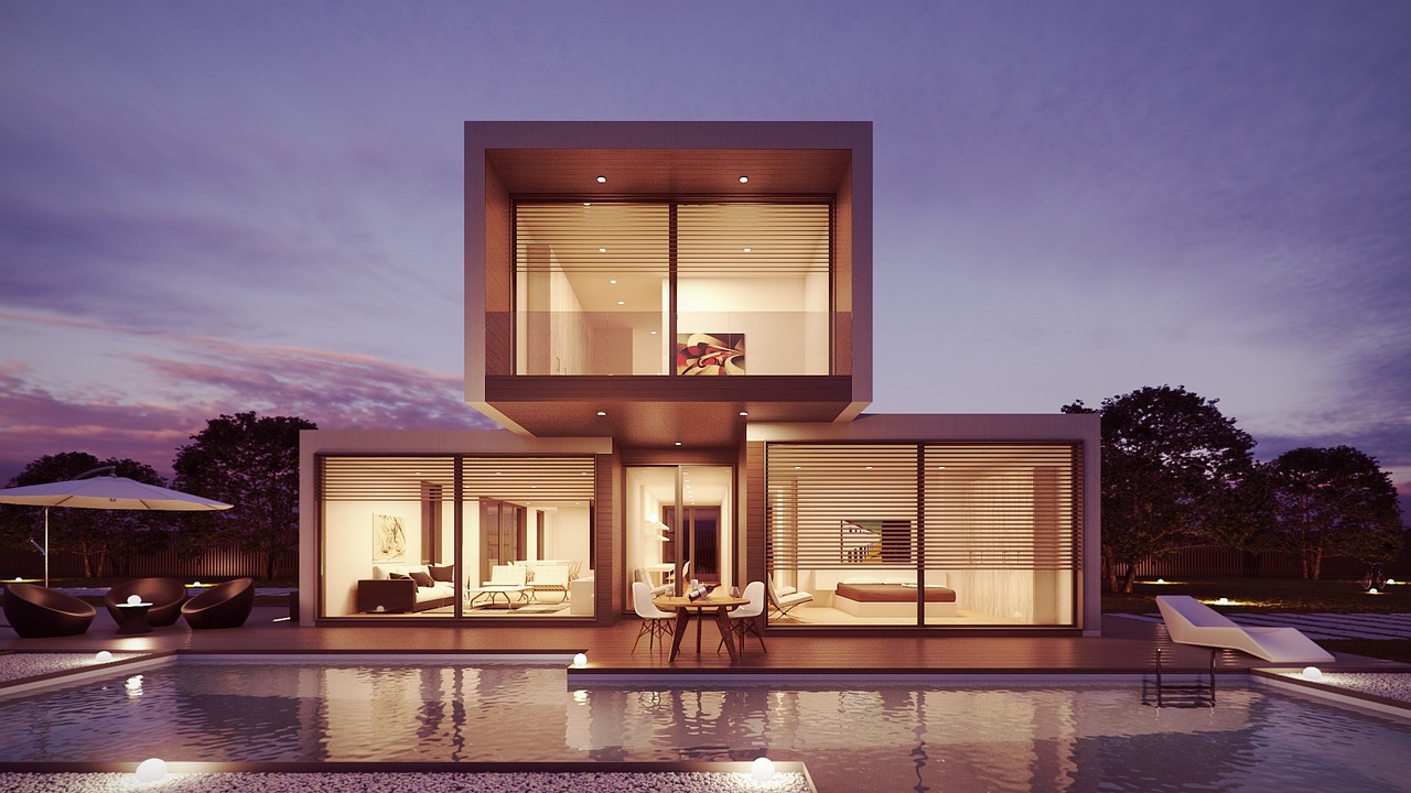 Modern two-storey villa with glass walls glowing at dusk beside a lit swimming pool