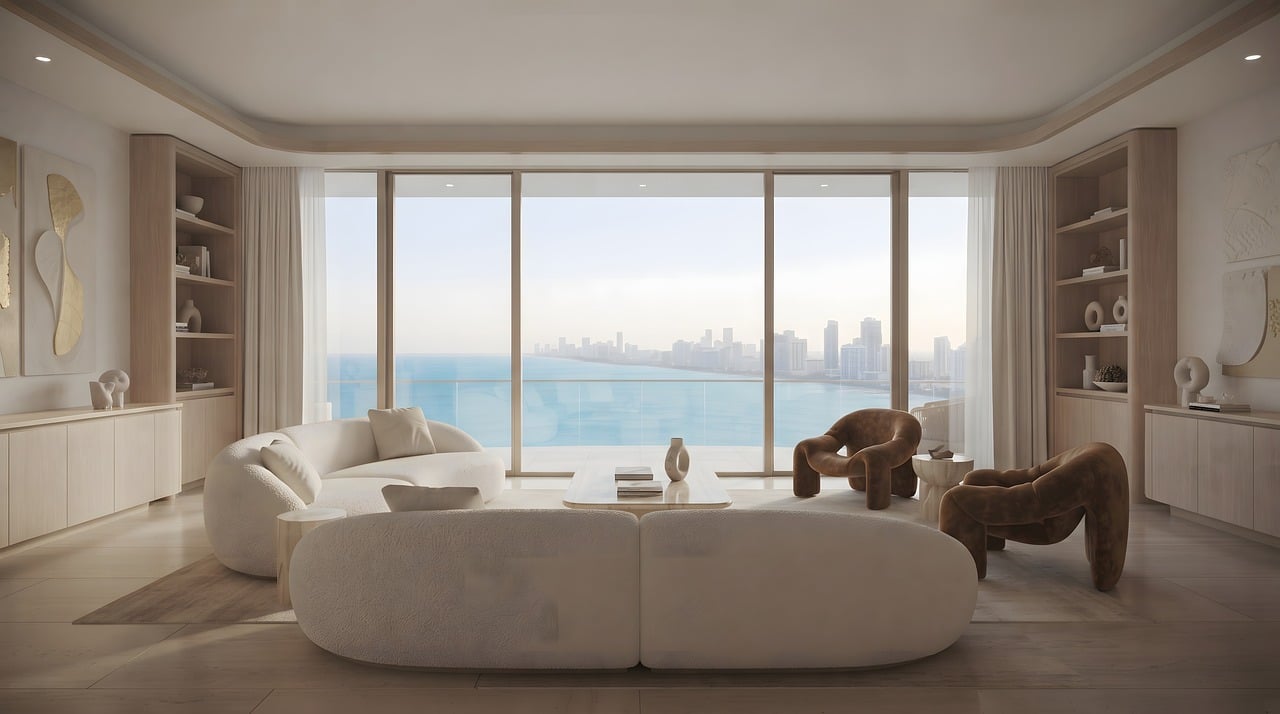 Bright apartment living room with cream sofas and armchairs facing a wide window onto the sea and a distant skyline